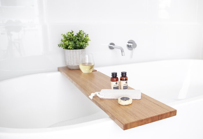 Jemmervale wooden bath tray shown with a glass of wine and soap.
