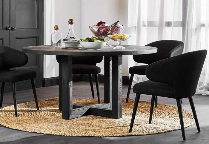 Black dining table with geometric legs adorned with bowls of food.
