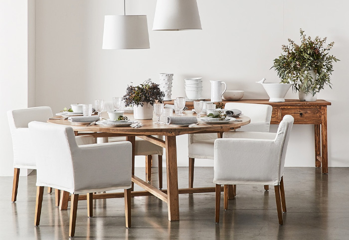 Family dining table setting with timber table and white upholstered chairs. 