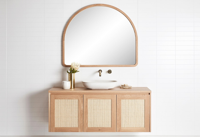 Timber curved mirror wall-mounted above a wooden vanity.