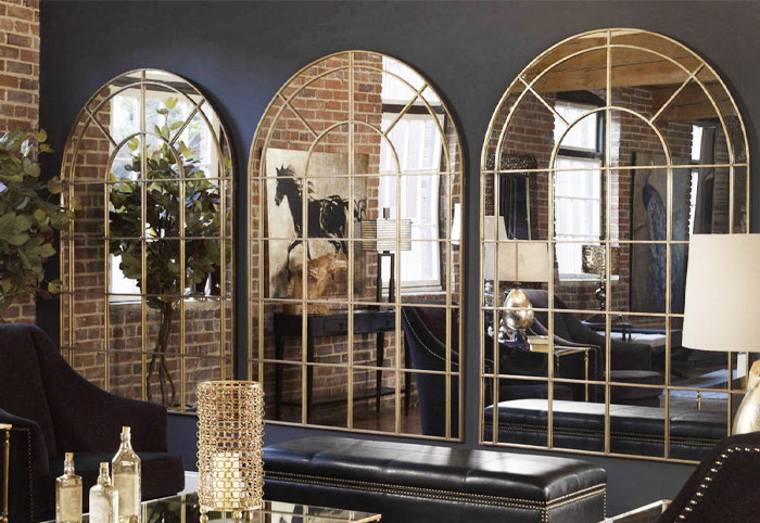 Three luxurious arched mirrors wall mounted in a row against a charcoal wall in a formal living room.