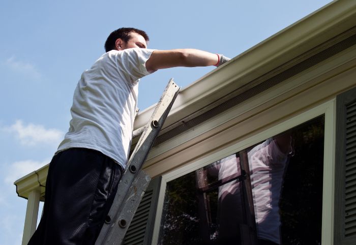 Using a ladder to clean the gutters