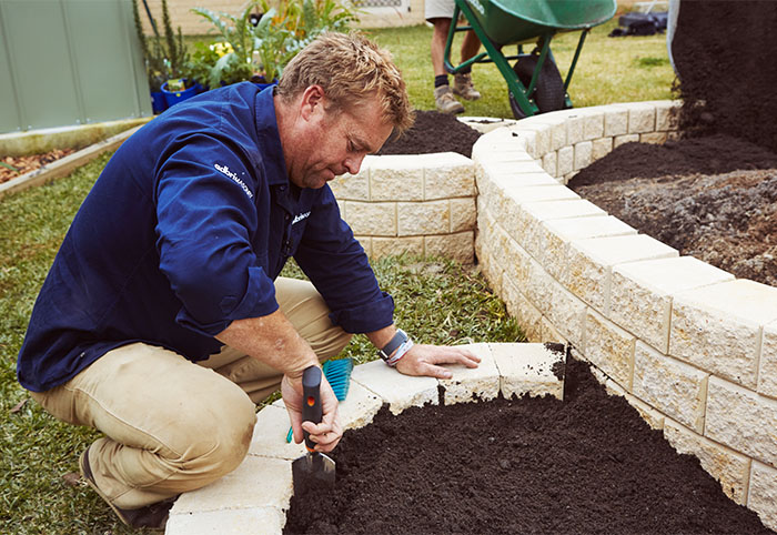 Jason Hodges adding soil to his veggie patch made of Miniwall blocks.