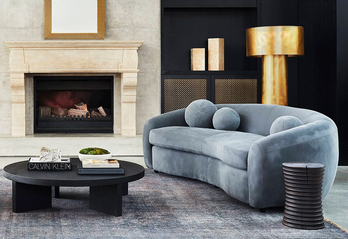 Blue velvet sofa next to a black coffee table and fireplace.