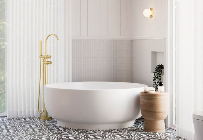 White Omnia round stone bathtub with gold tapware