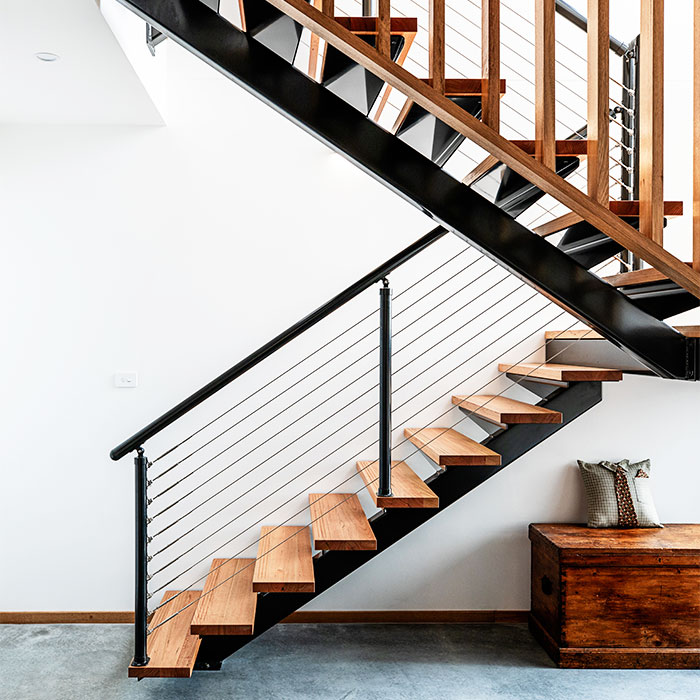 Residential staircase with black rails and wooden steps.