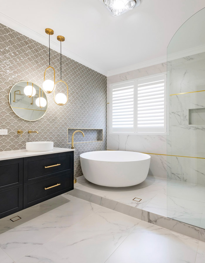 Split-level bathroom with gold taps and round tub.