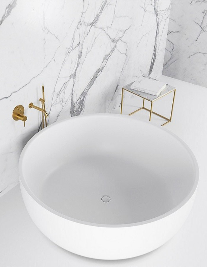White bathroom with gold taps and marble walls.