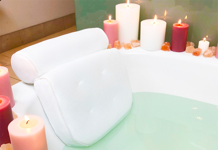 Padded bath support in a tub surrounded with candles.