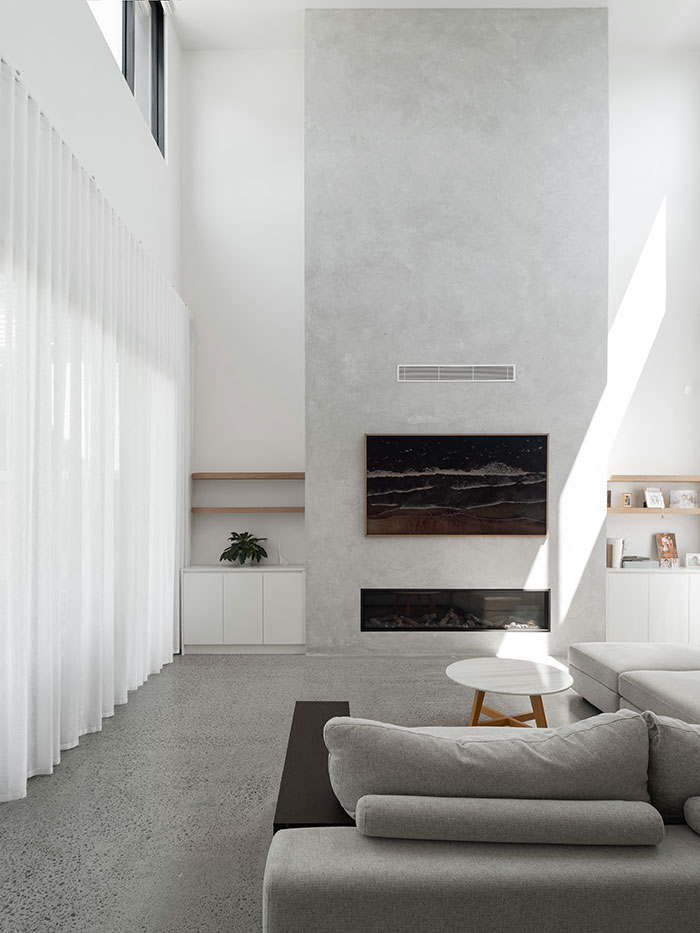 Living room of large modern home with polished concrete floors and grey sofa.
