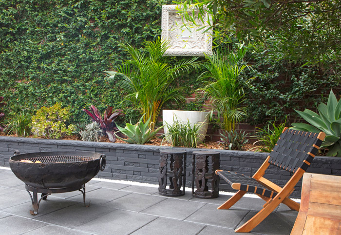 Balinese-themed courtyard with a fire pit and concrete brick retaining wall.