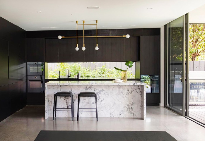 Black kitchen by Famous Joinery featuring a window splashback.