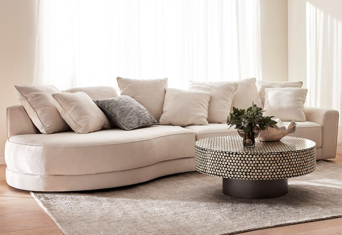 Curved Cabarita Sofa positioned next to a round coffee table.