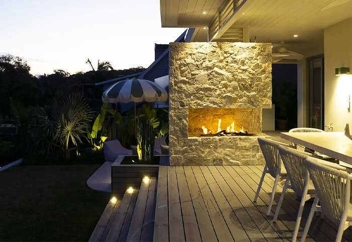 Gas fireplace built into a stone wall on a beautiful deck. 