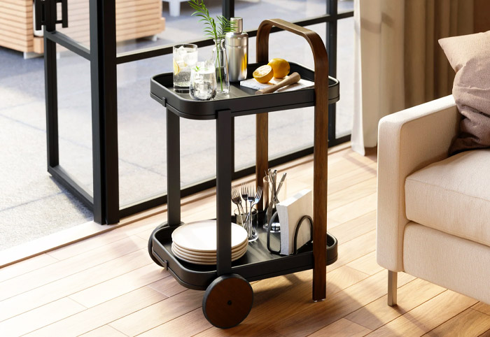 Small black and walnut bar trolley next to an open door and patio.
