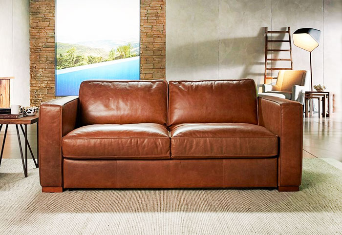 Nick Scali tan leather sofa bed in a living room.