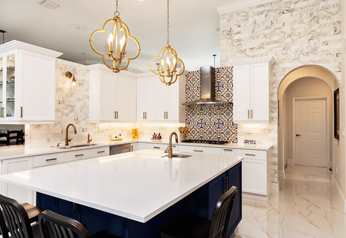 A white kitchen with blue island bench and gold tapware.