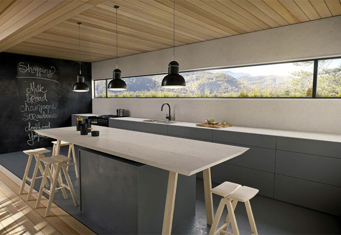 Modern kitchen with an extra-long window above the sink looking out to hills. 