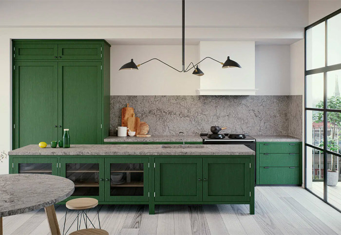 Green kitchen cabinets with a grey stone bench and splashback.