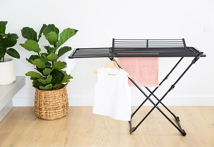 Black clothes rack on a hardwood floor with a white shirt hanging from it. 