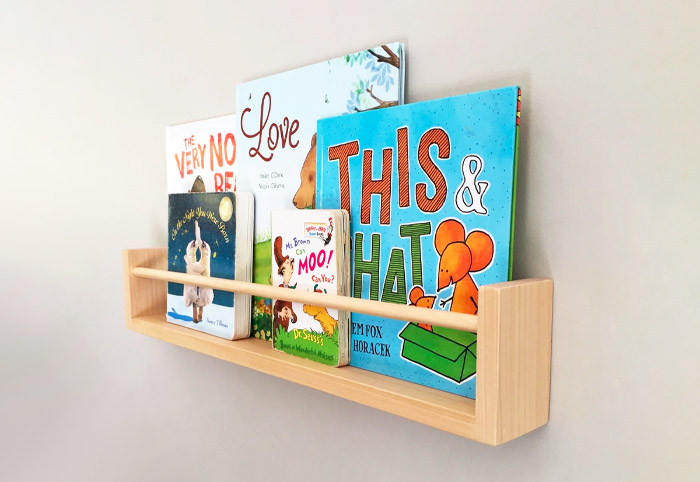 Kids' wooden bookshelf on a wall filled with picture books.