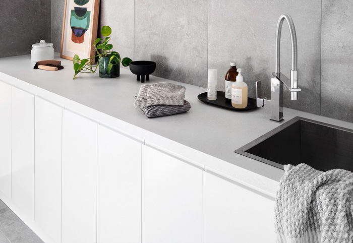 Contemporary kitchen sink with chrome tap and hidden pulls on white cabinetry.