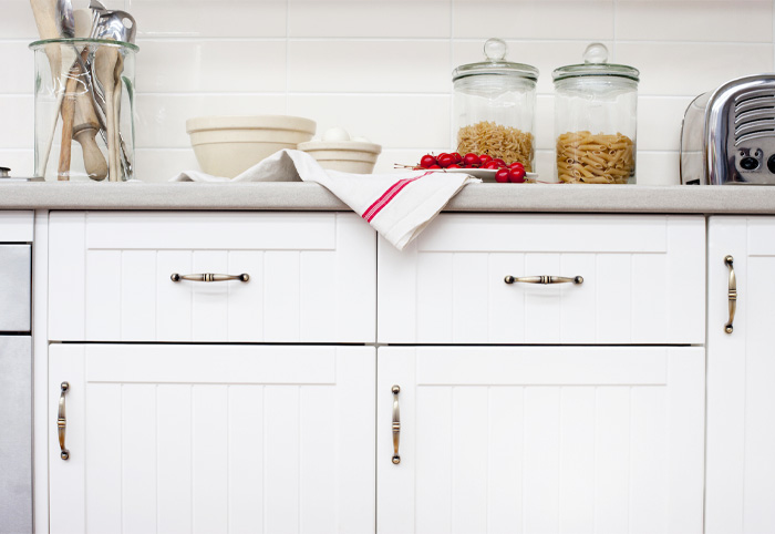 Brass antique-style handles on white shaker kitchen cupboards.
