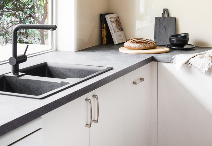Contemporary white kitchen with black undermount sink and chunky silver handles.