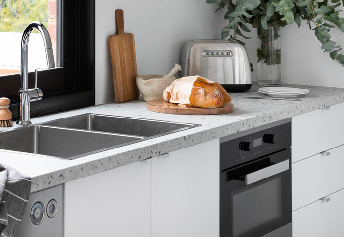 Modern kitchen sink with stainless steel tap, white cabinets and discrete pull handles.
