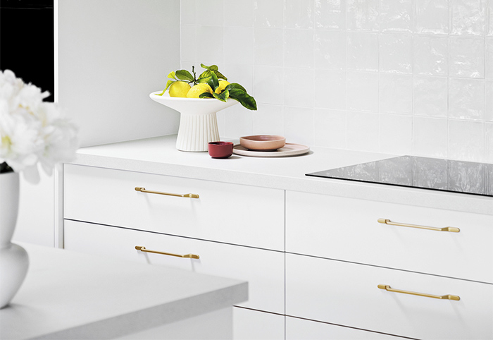 Long white kitchen drawers with modern gold handles.