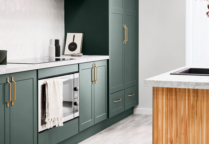 Olive green kitchen cabinets with worn gold handles.