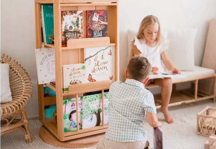 Children reading books next to a rotating wooden bookshelf.