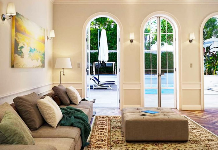 Living room French Provincial windows opening out to a terrace and swimming pool.