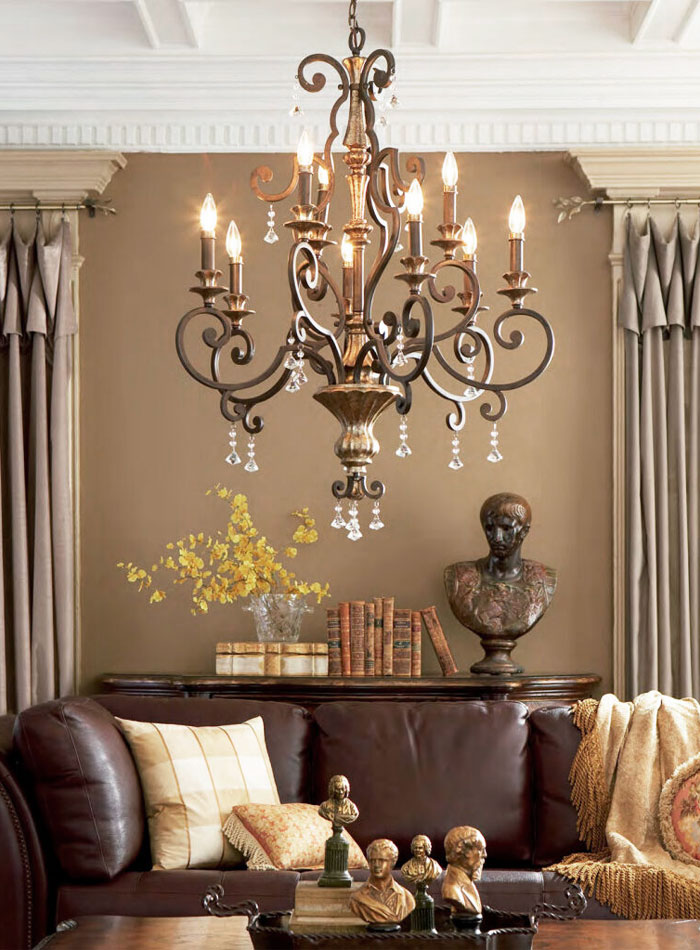 A French Provincial chandelier hanging from a ceiling above a brown leather sofa.