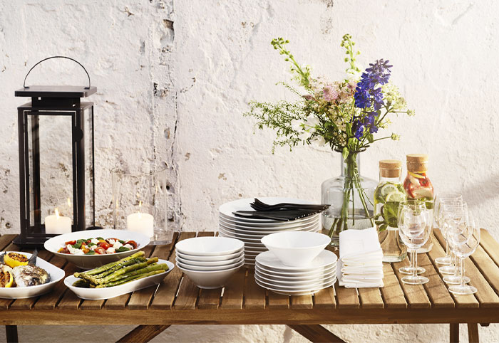 Outdoor table filled with tableware and food for a celebration.