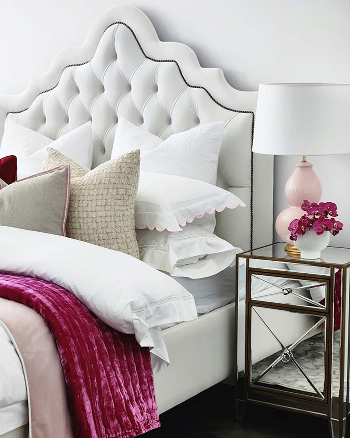Tufted upholstered bed with white and pink linen.
