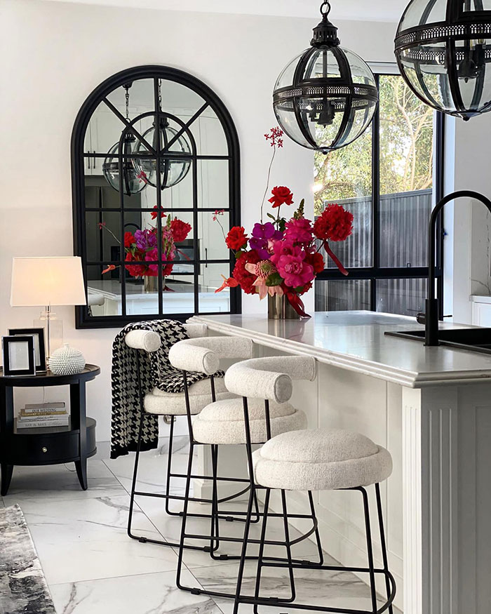 Monochrome kitchen with arched mirror and round French pendants.