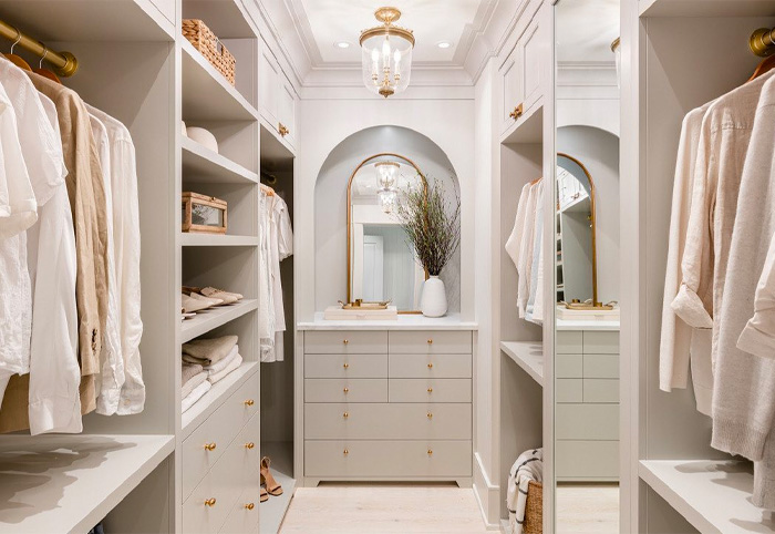 Walk-in closet with arched mirror and gold handles. 