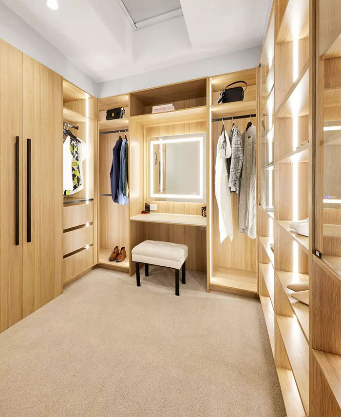 A large walk-in closet fitted with wooden shelving and a central dressing table.