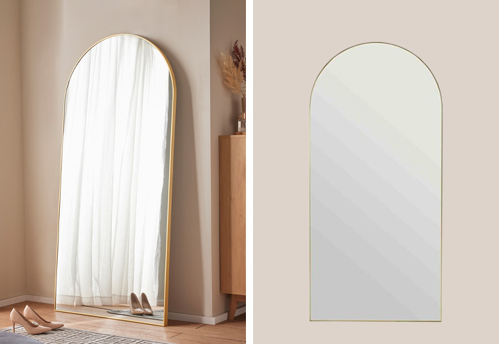 Gold mirror shown leaning against a wall in the corner of a bedroom.