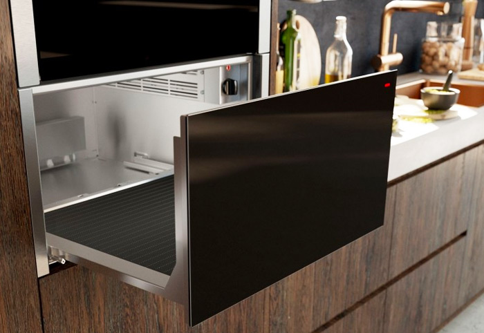 Modern kitchen heating drawer shown integrated under an oven.