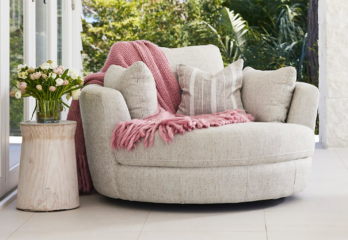 Fabric Snuggle swivel armchair on an outside terrace with garden in the background.
