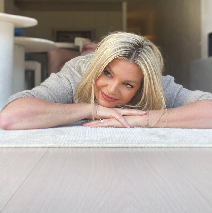 Rebecca Maddern lying on a white rug in her living room.