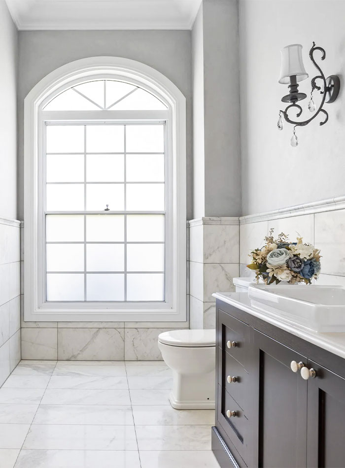 Large arched window in a narrow bathroom.
