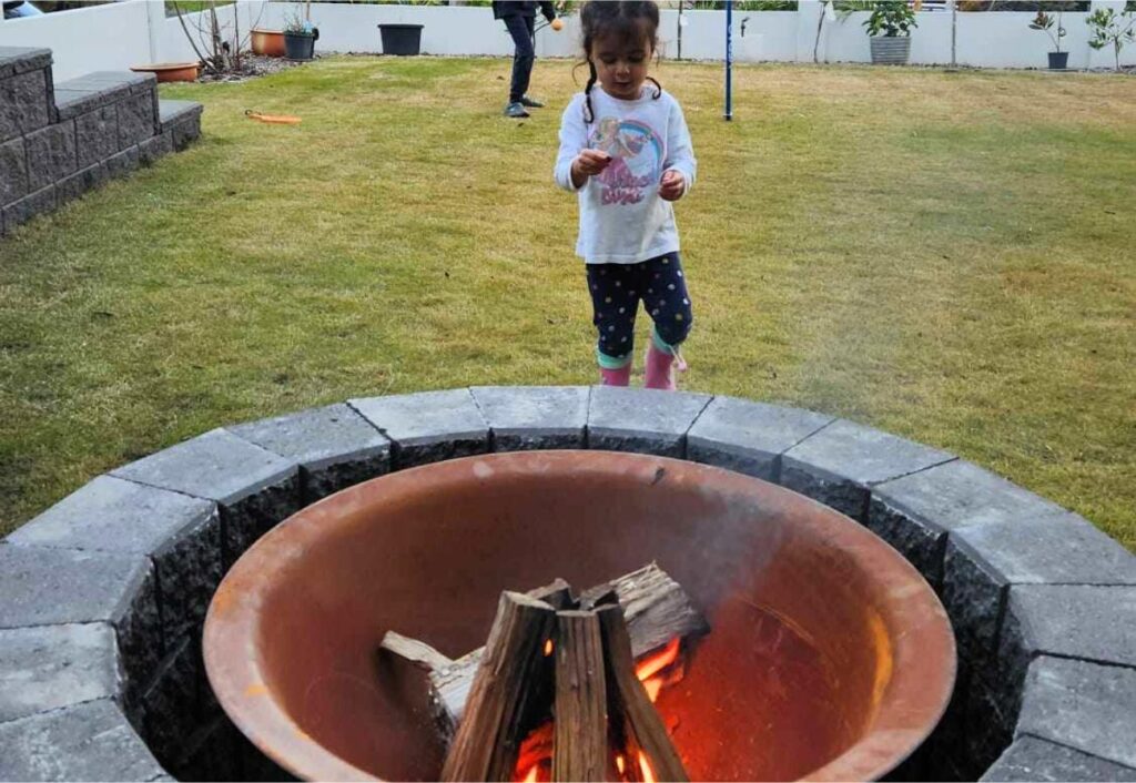 A child walks towards a DIY fire pit.