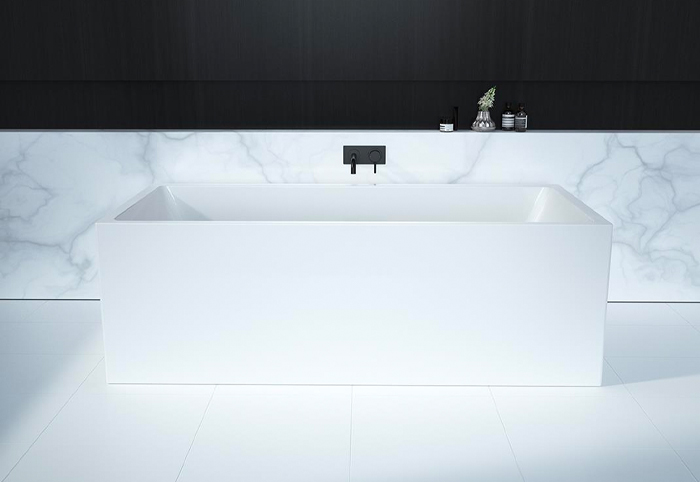 Modern square edge bathtub in a monochrome bathroom, with black tapware.
