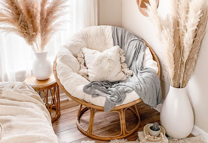 Natural wicker occasional seat on a wooden floor, surrounded by boho decor.