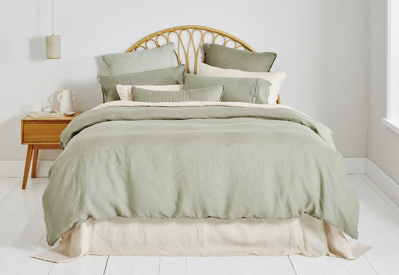 Sage green Dri-Glo quilt cover on a Queen bed with a rattan bedhead.