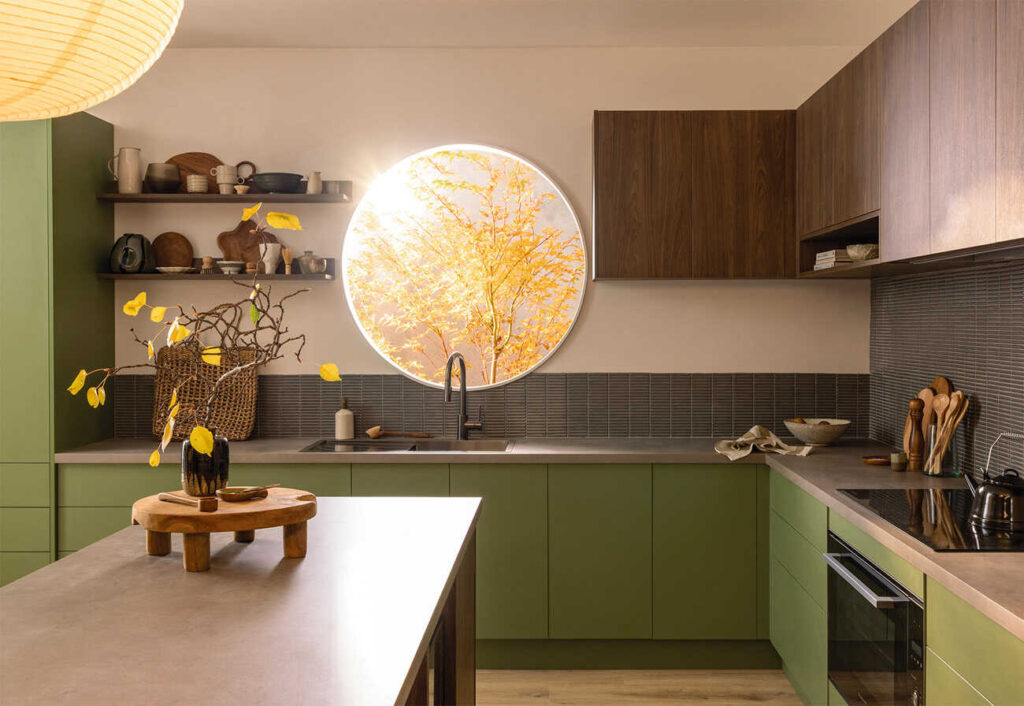 Kaboodle kitchen with circular window and green cabinetry.