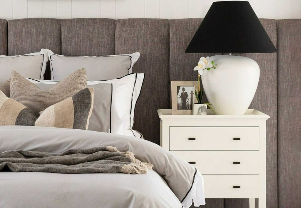 Modern bedroom with a grey headboard and white hamptons-style bedside table.